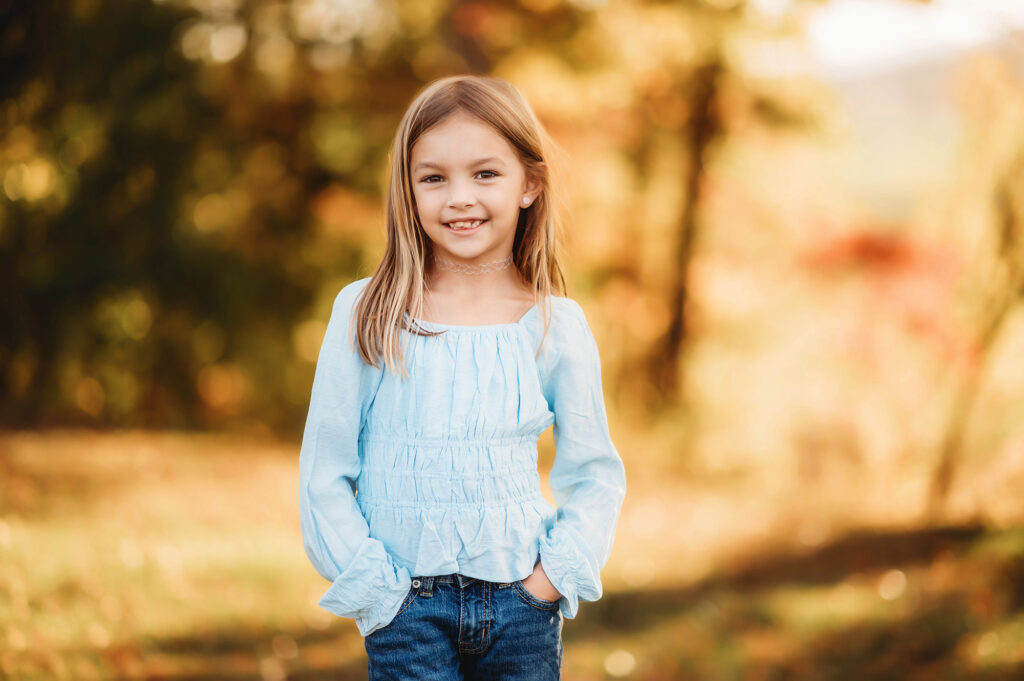 Little girl smiles at the camera during her family's fall family photoshoot in Asheville after learning about Family Photos Locations in Asheville.