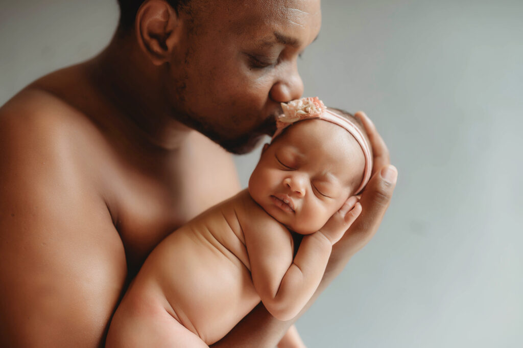 Father kisses his infant daughter during Newborn Photoshoot in Asheville. 