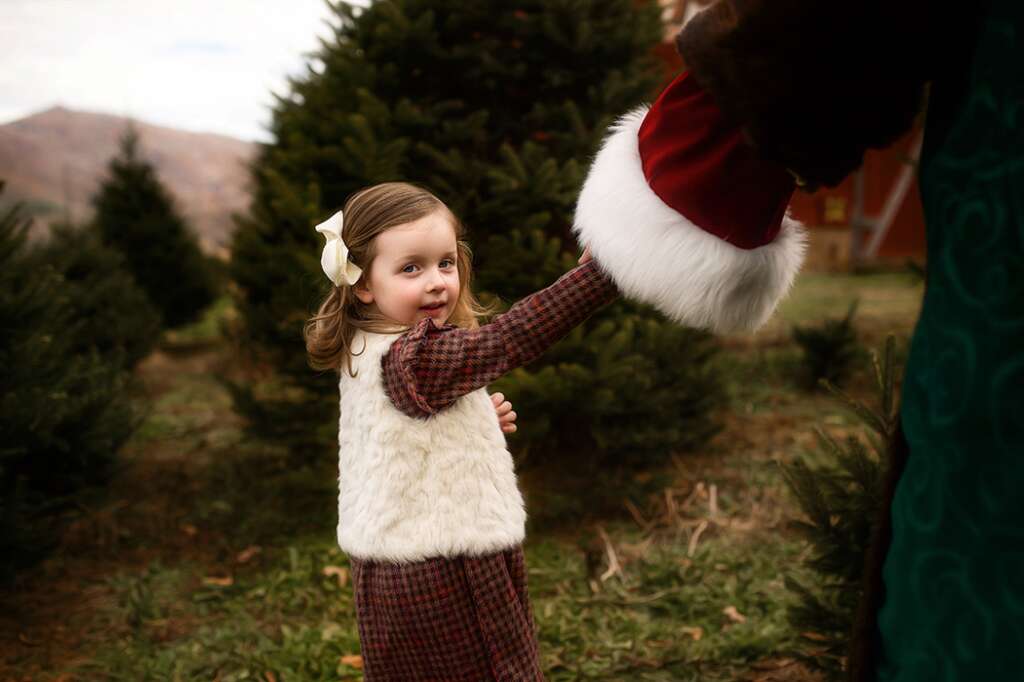 Little girl holds Santa's hand